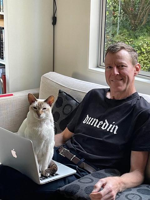 Matt Pestle sitting on a couch with a laptop and a white cat